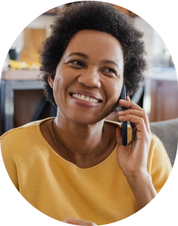 African American woman in yellow blouse, smiling, while holding a mobile phone to her ear